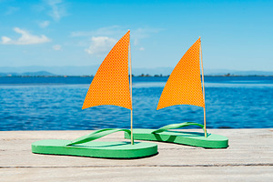 green flip-flop sailboats beside calm water, a Photo by Nito