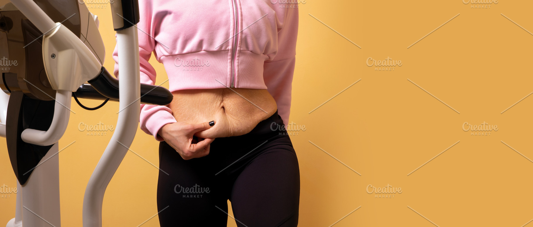 Close-up of a woman in gymwear pinching stomach skin while stand, a Person Photo by Ales Munt