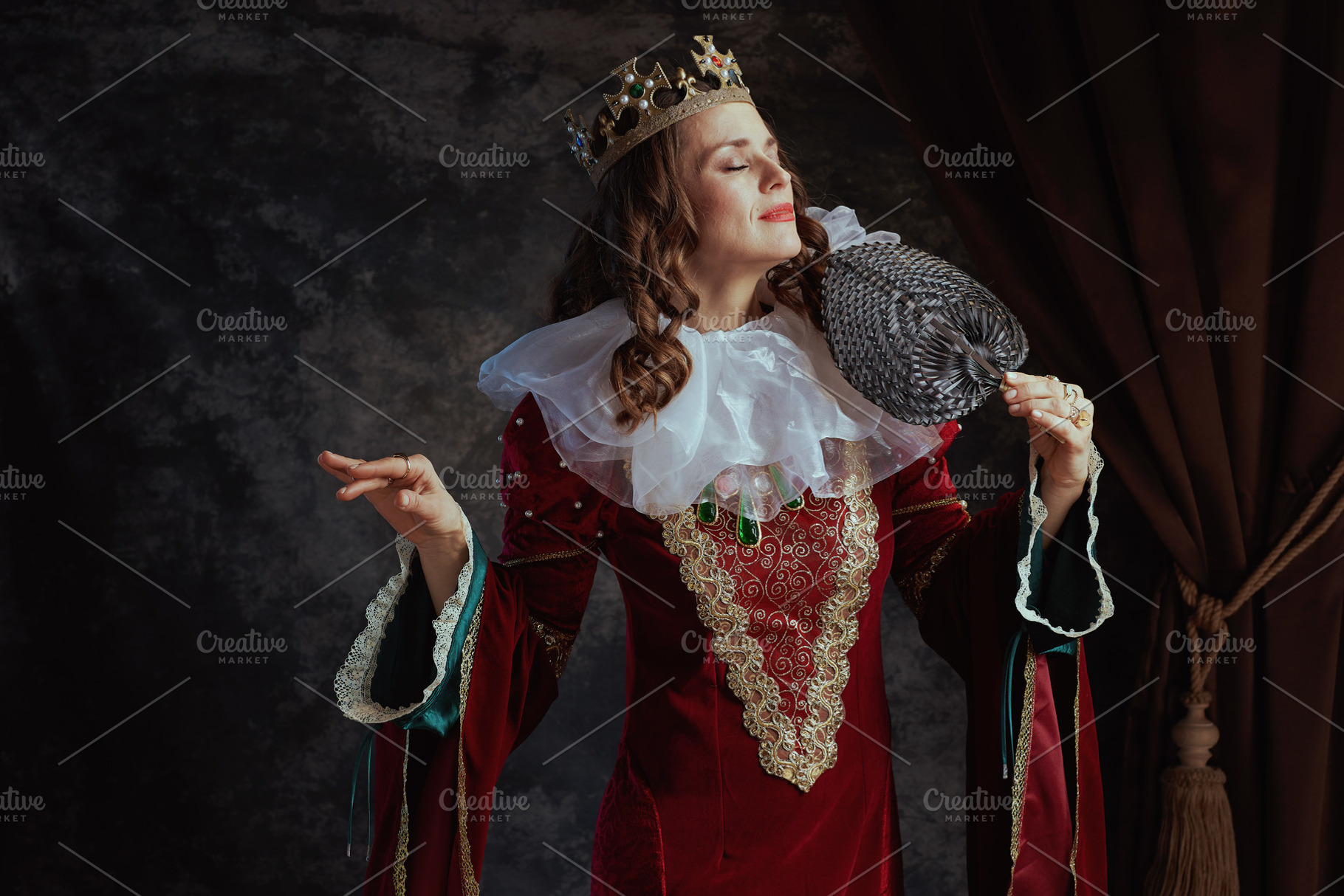 medieval queen in red dress with fan, white collar and crown, a Person Photo by Alliance Images