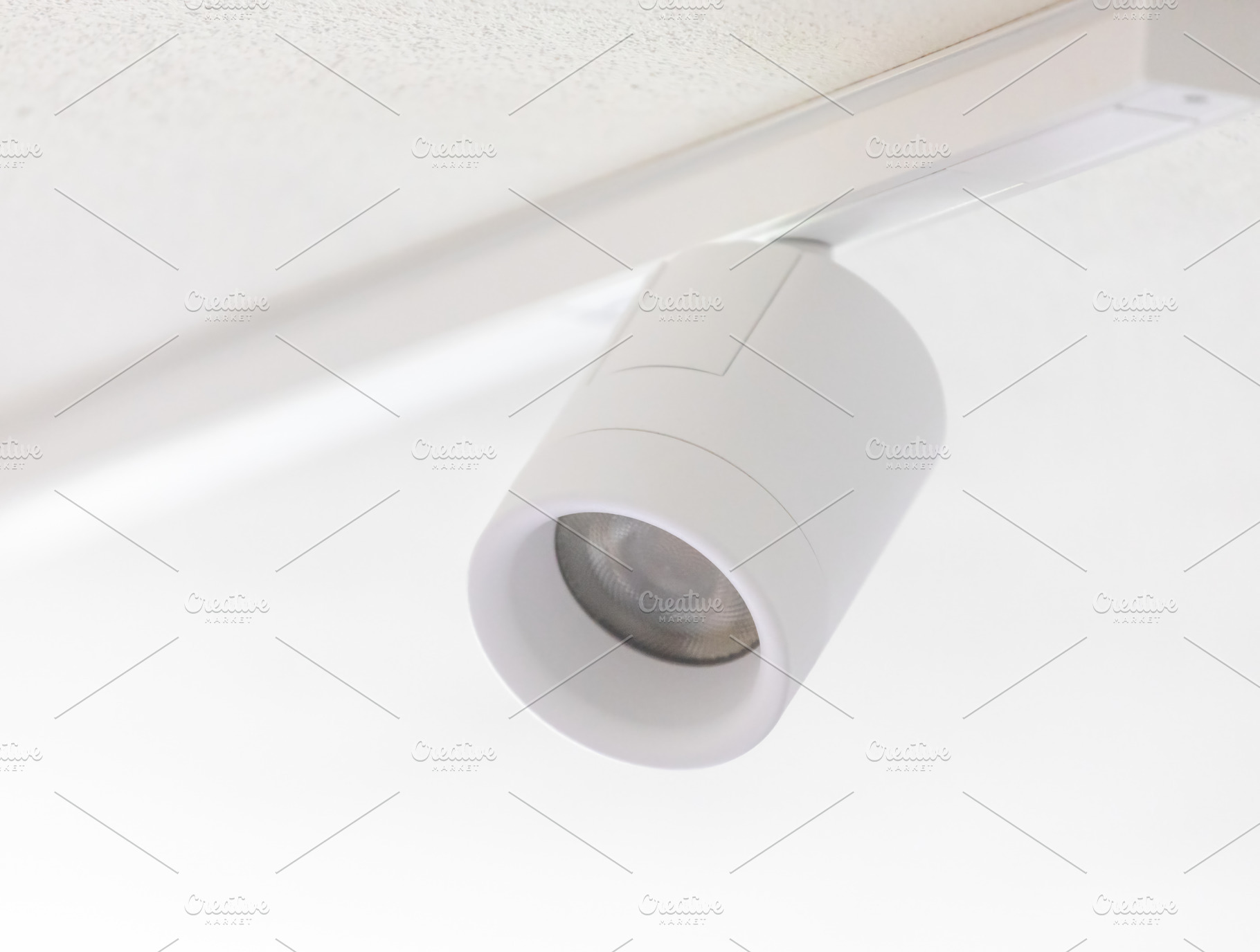 White cylindrical spotlight hanging from ceiling track lighting system, an Architecture Photo by Antonio Gravante Market