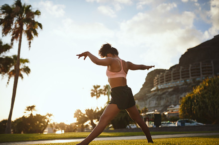 Fit young woman practicing yoga in a city park