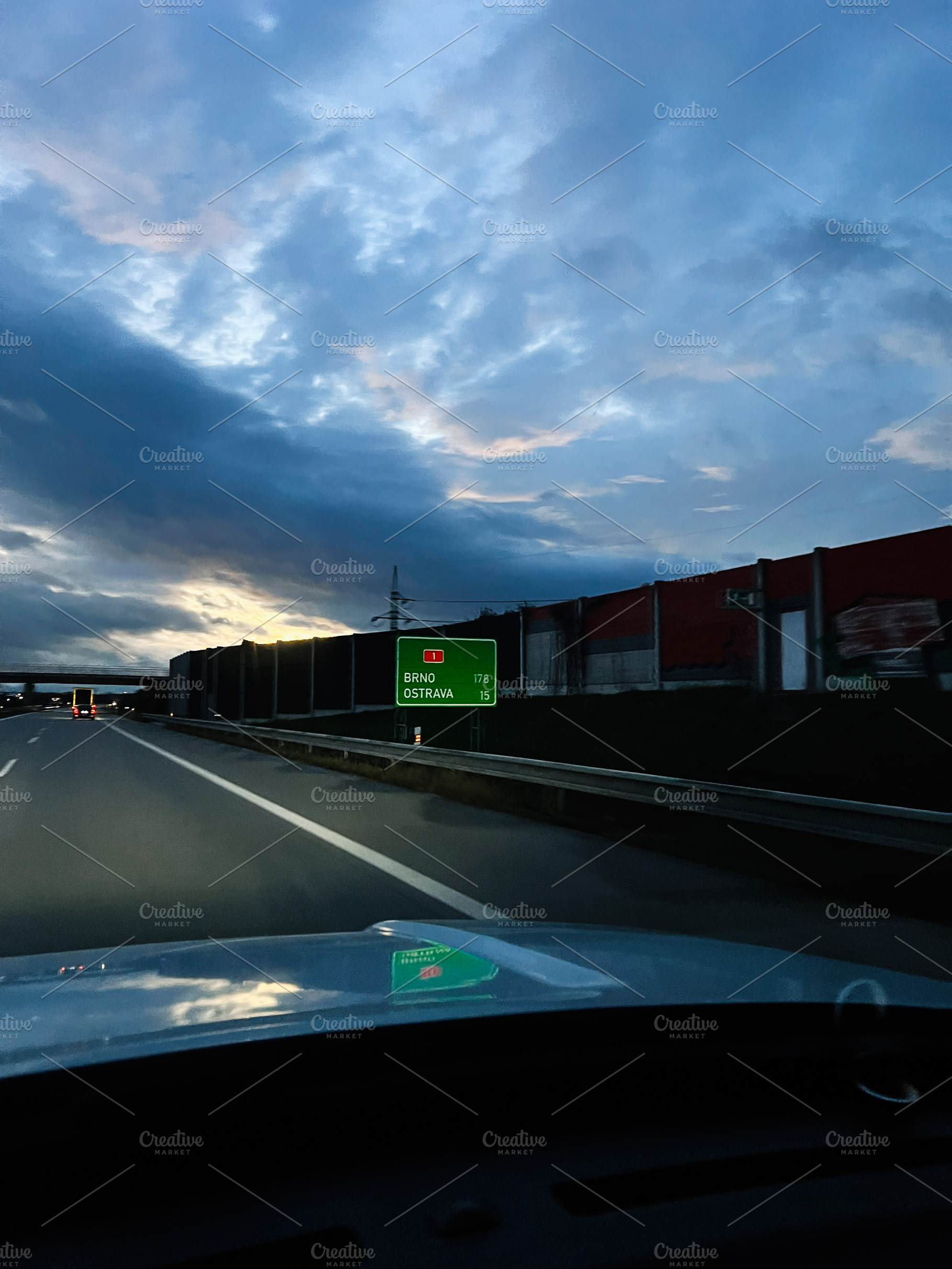 Driving at dusk on a highway toward Brno and Ostrava with a green road sign, a Photo by AS photostudio