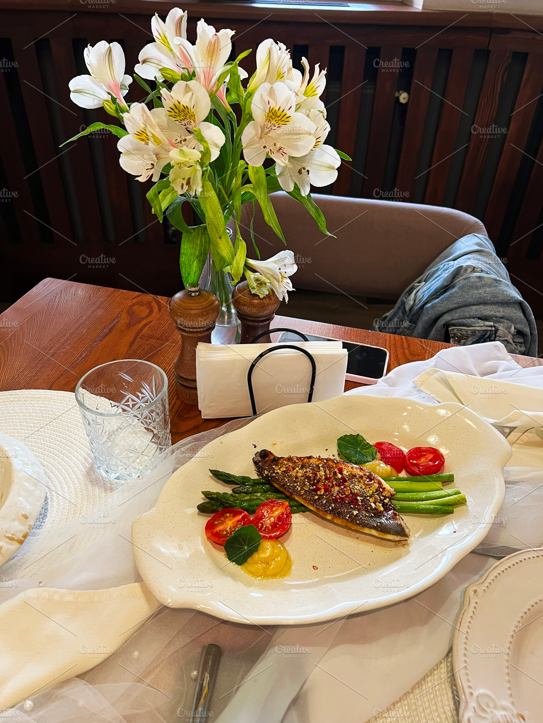 Elegant meal featuring grilled fish with vegetables and a floral table centerpi, a Photo by AS photostudio