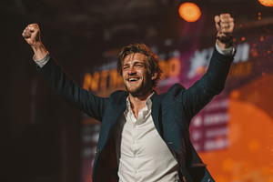 Ecstatic man celebrating success on a vibrant stage with bright lighting, a Person Photo by AS photostudio