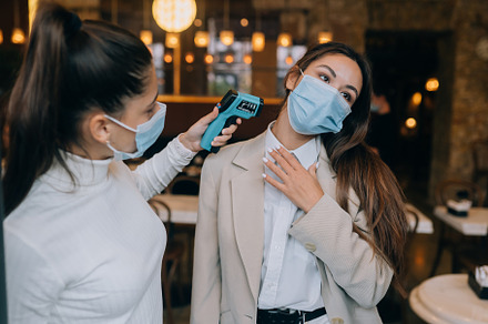 Woman measuring body temperature with contactless body thermometer