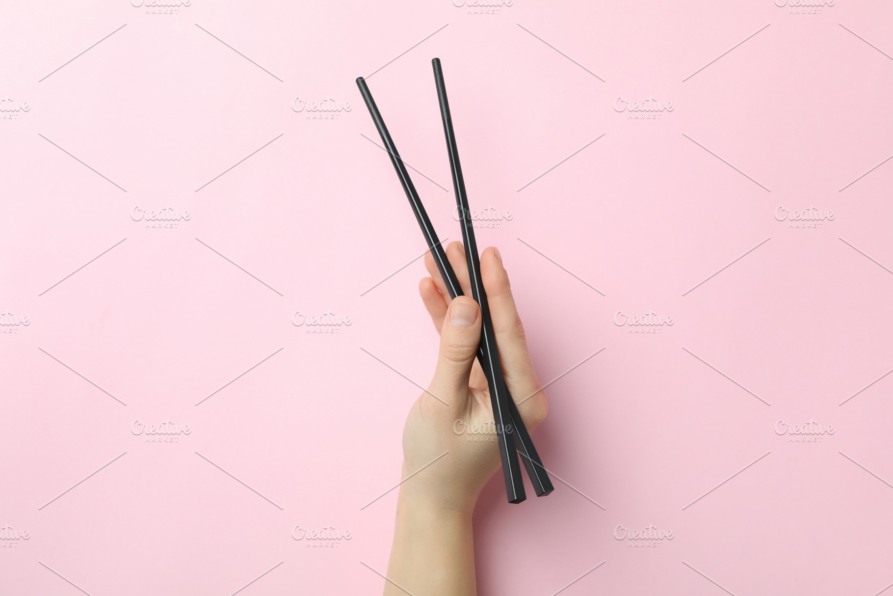 Female hand holding chopsticks on pink background, a Food & Drink Photo by AtlasStudio PRO
