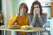 Daughter and mother drink tea in the containing home, cups, and ...