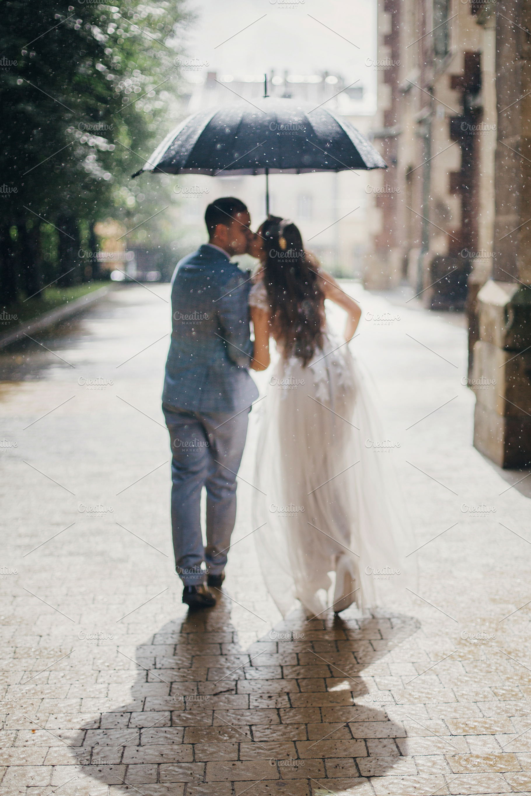 Rain drops on background of blurred stylish bride and groom walk, a Person Photo by Sonjachni