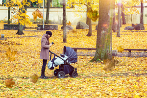 Mother with baby pram in autumn park, a Person Photo by BOOCYS