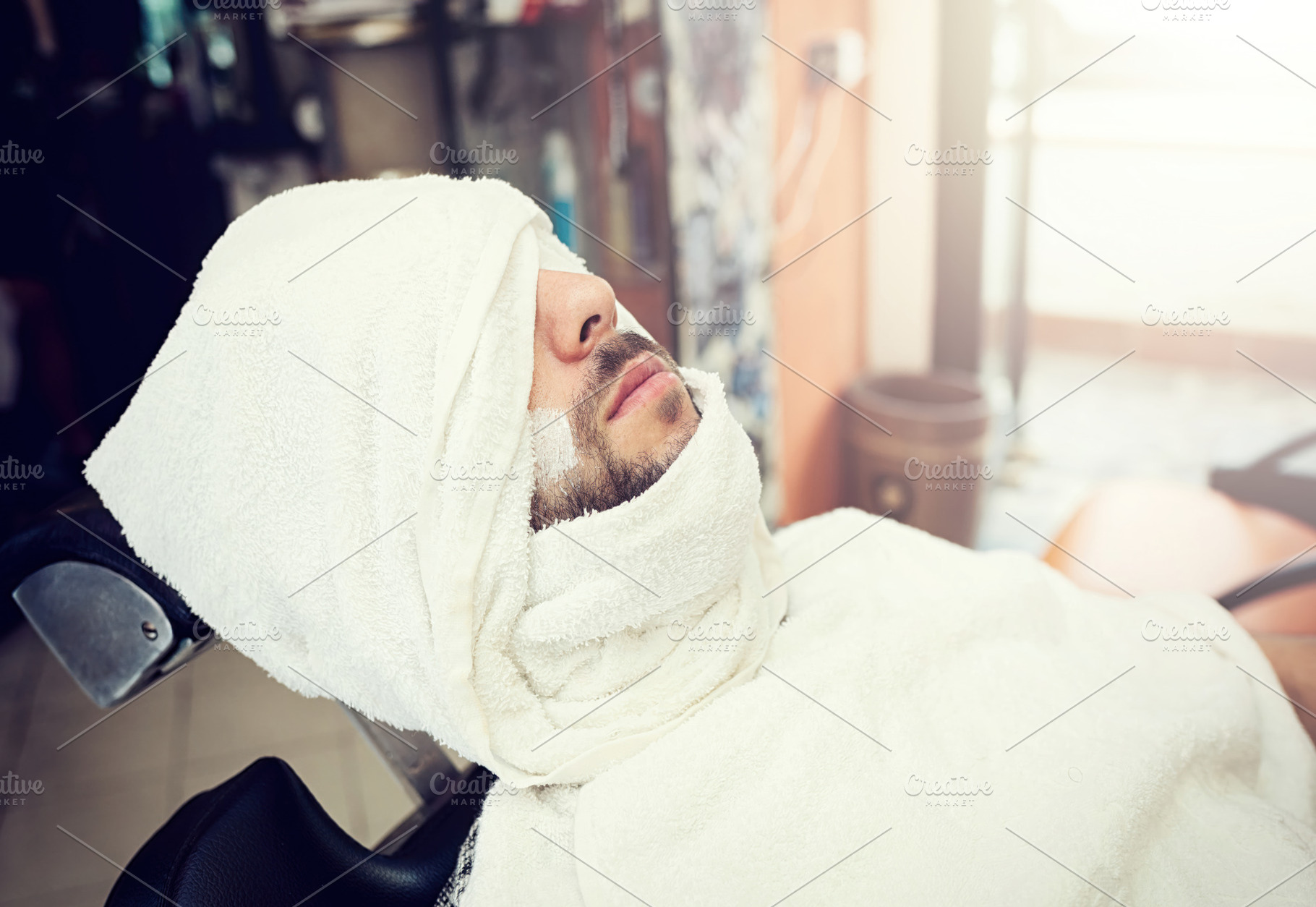 Mature male with beard receiving professional grooming, reclining in barbershop, a Person Photo by Antonio Gravante Market