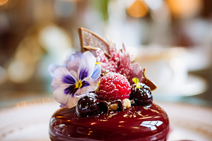 Gourmet berry dessert with edible flower garnish on a white plat, a Photo by Studio ANNA