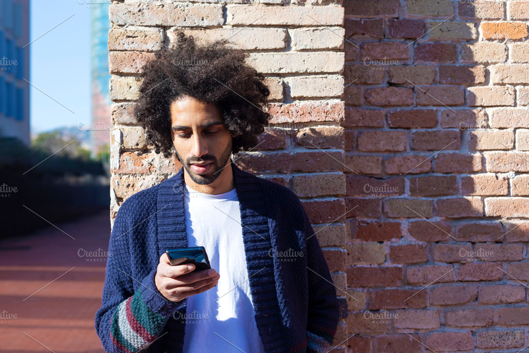 Young afro man using cellphone outdoor, a Person Photo by 2Design