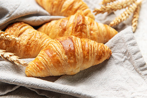 Freshly baked croissants resting on a linen cloth with wheat sta, a Food & Drink Photo by Olena Rudo