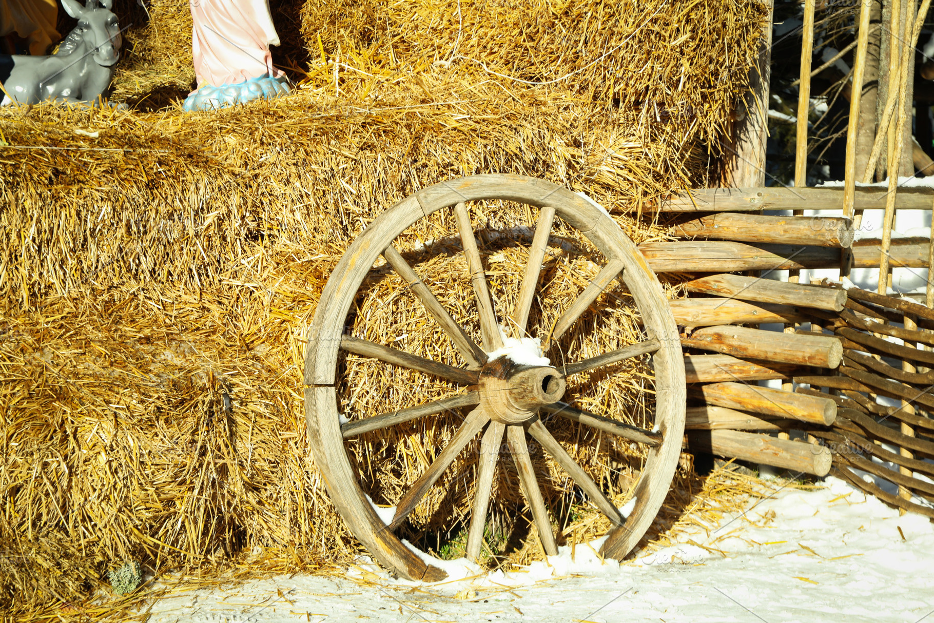 Wooden wheel near straw outdoor in winter season, a Nature Photo by AtlasStudio
