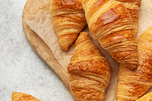 Freshly baked croissants on wooden board, a Food & Drink Photo by Olena Rudo
