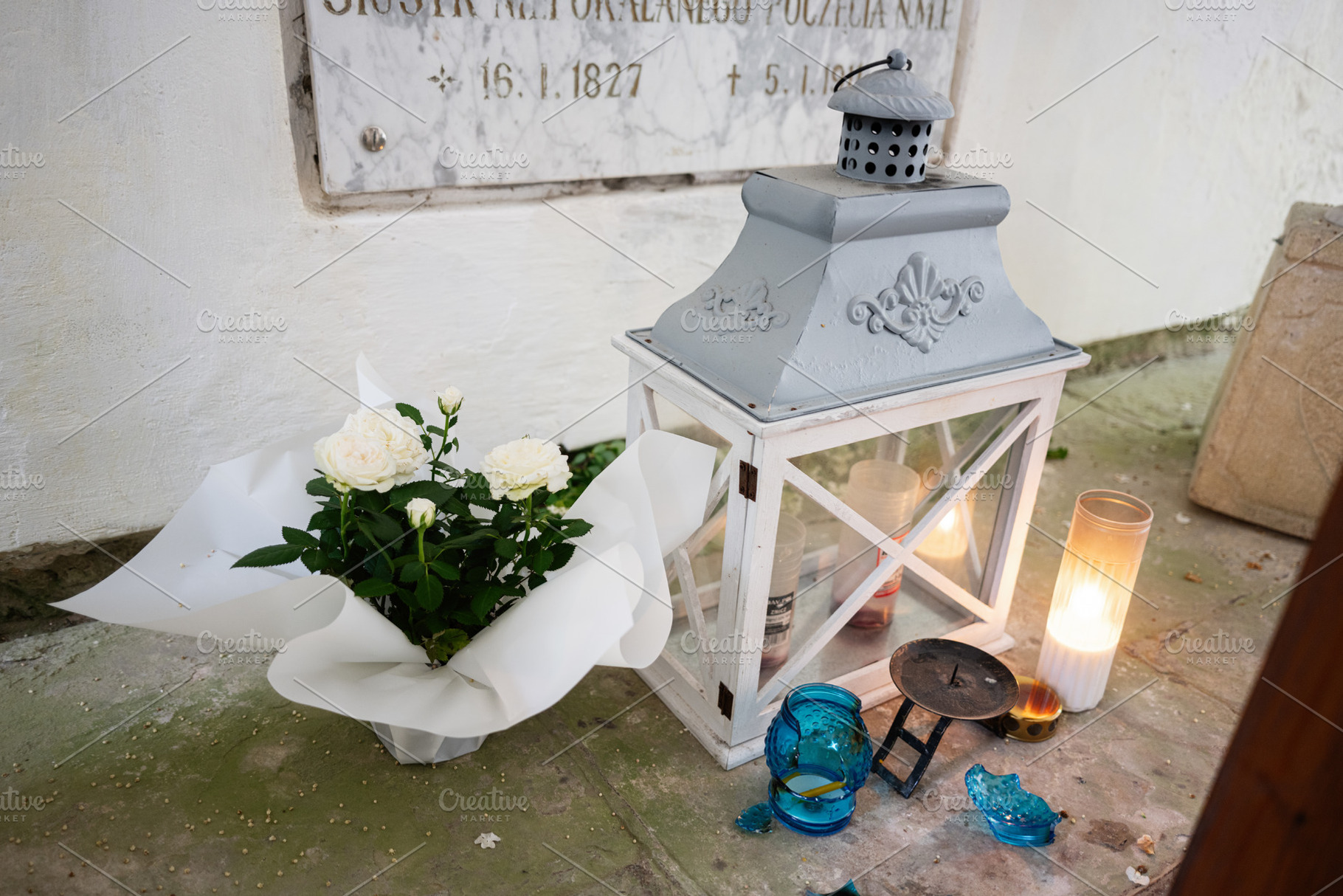 Serene commemoration with floral arrangement and candlelit lantern in memorial, a Photo by AS photostudio