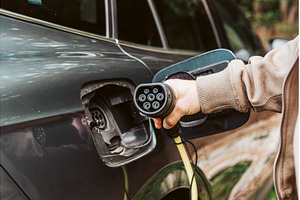 Man charging electric car, hodding, a Transportation Photo by HalfPoint