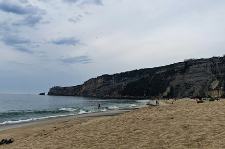 Peaceful coastal view of Nazare Beach under cloudy skies in Portugal, a Photo by AS photostudio