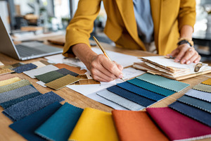 Designer selecting fabric swatches at worktable, an Arts & Entertainment Photo by AlyaAnd