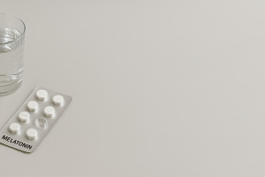 Melatonin pills with glass on white, a Photo by Dvoevnore photos