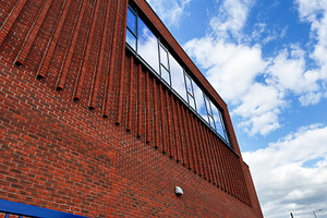 Modern red brick building facade with reflective windows and bri