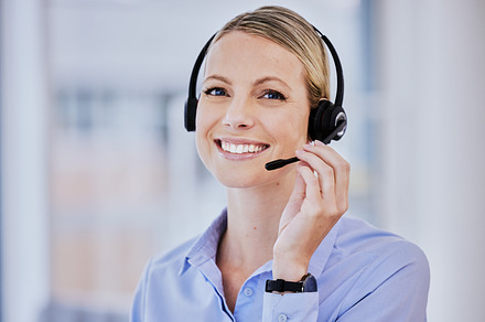 Portrait of young caucasian female call centre agent talking on headset while working in an office. Confident and happy businesswoman consulting and operating a helpdesk for customer sales and service support, a Photo by Peopleimages.com