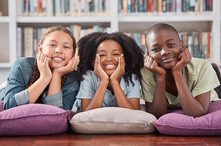 Children in library, portrait with learning and education, happy with books and academic growth. Knowledge, information and development with young students, happiness to learn and school activity, a Photo by Peopleimages.com
