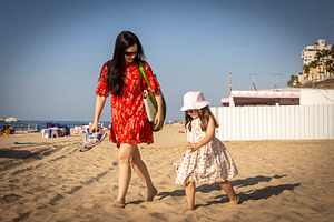 Mother and daughter walking barefoot on the beach, with the moth, a Person Photo by Imaginarium