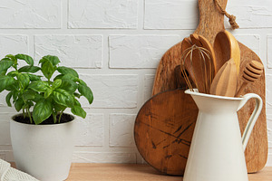 Kitchen utensils and basil plant creating a rustic culinary scen, a Food & Drink Photo by Olena Rudo