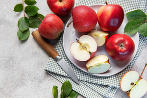 Fresh red apples whole and sliced on white plate with green leav, a Food & Drink Photo by Olena Rudo