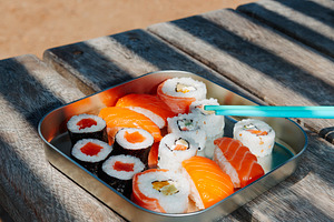 sushi and nigiri fill a metal lunch box on a table, a Photo by Nito