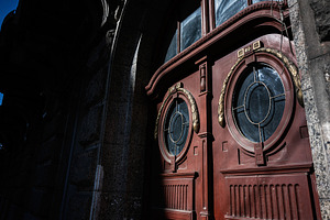Circular wooden doors with ornate detailing on historic building facade, a Photo by AS photostudio