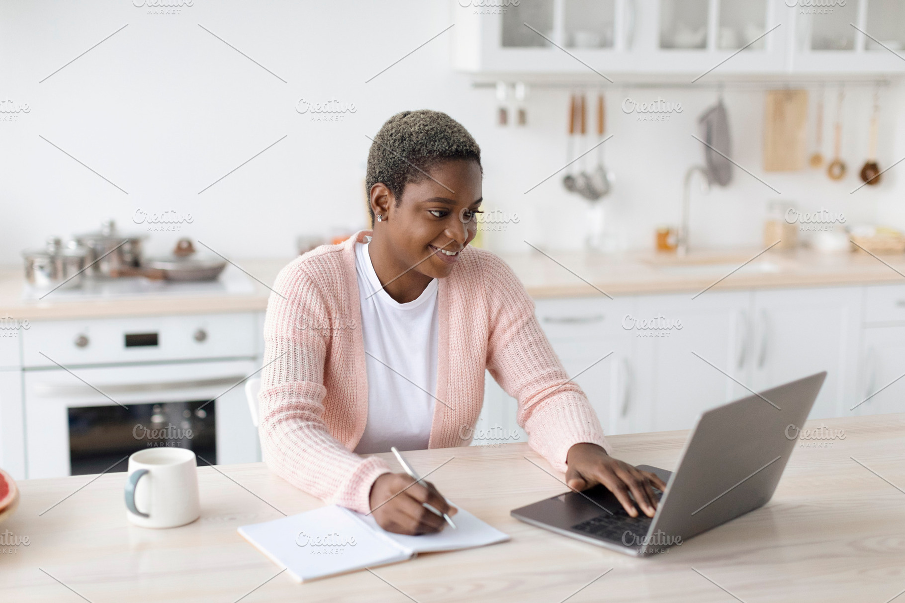 Smiling young african american woman in casual working on laptop in minimalist, a Person Photo by Prostock-Studio