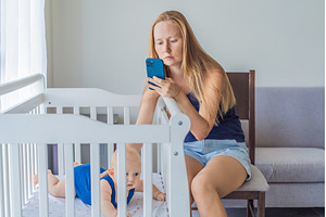 Very tired mother sitting by baby