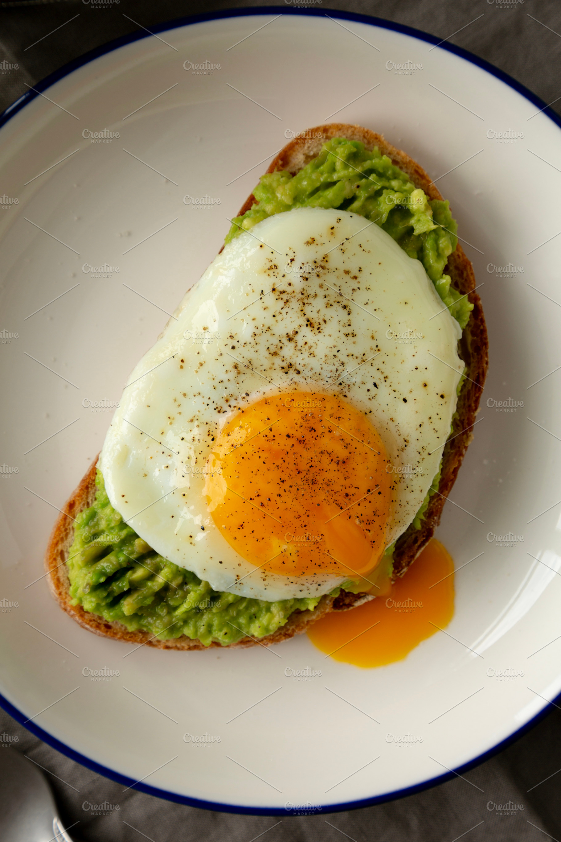 Homemade Avocado Toast with Egg on a Plate, top view. Close-up., a Food & Drink Photo by LiudmylaChuhunova