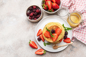 Stack of pancakes with fresh berries and honey for breakfast, a Food & Drink Photo by Olena Rudo