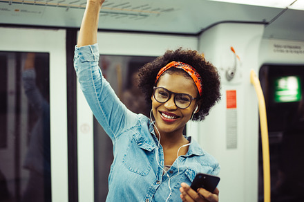 Smiling young african woman listening to music on the subway featuring 20s, a Person Photo by Stefan & Janni