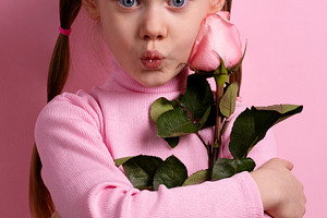 Cute young girl in pink with pigtails holding a rose and making, a Person Photo by Ales Munt