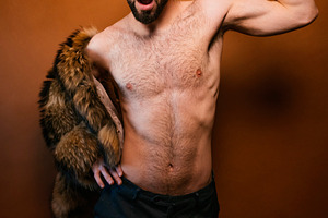 Confident man flexing muscle wearing yellow beanie, a Photo by karrastock