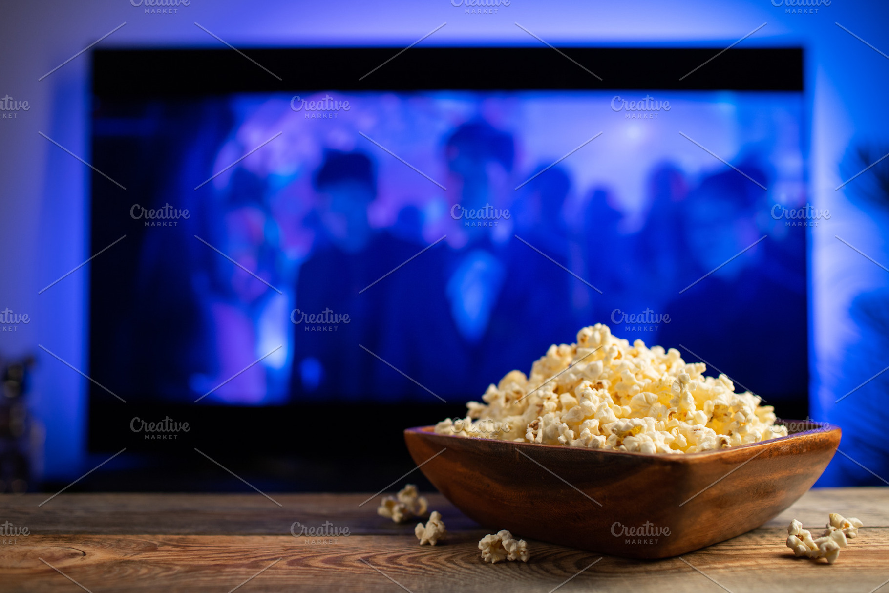 A wooden bowl of popcorn and remote control in the background the TV works. Eve, a Food & Drink Photo by Budarinphoto