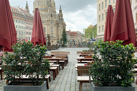 Outdoor café view with red umbrellas, benches, and green plants