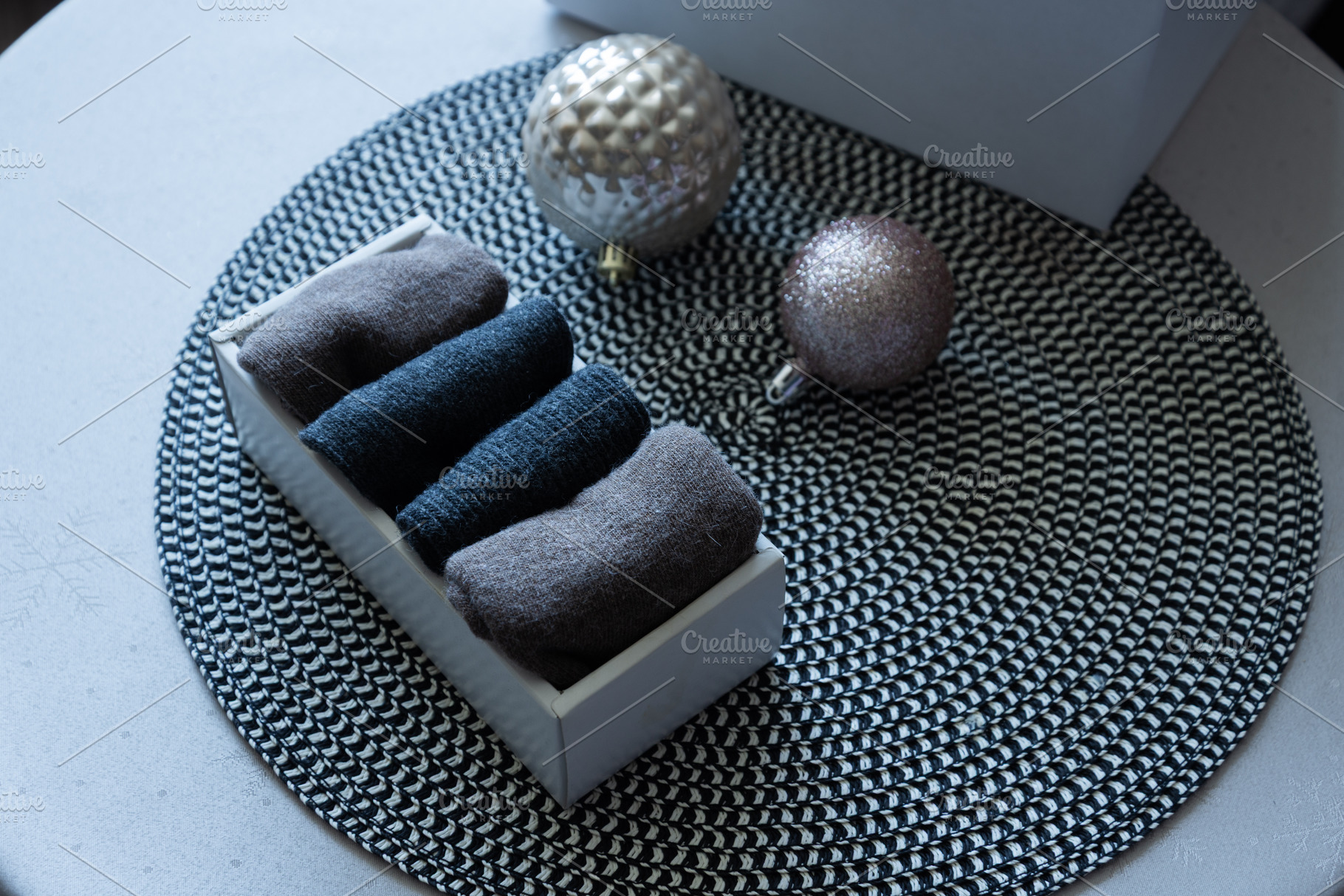 Folded knit textiles in box with Christmas ornaments on table, an Industrial Photo by MDBildes