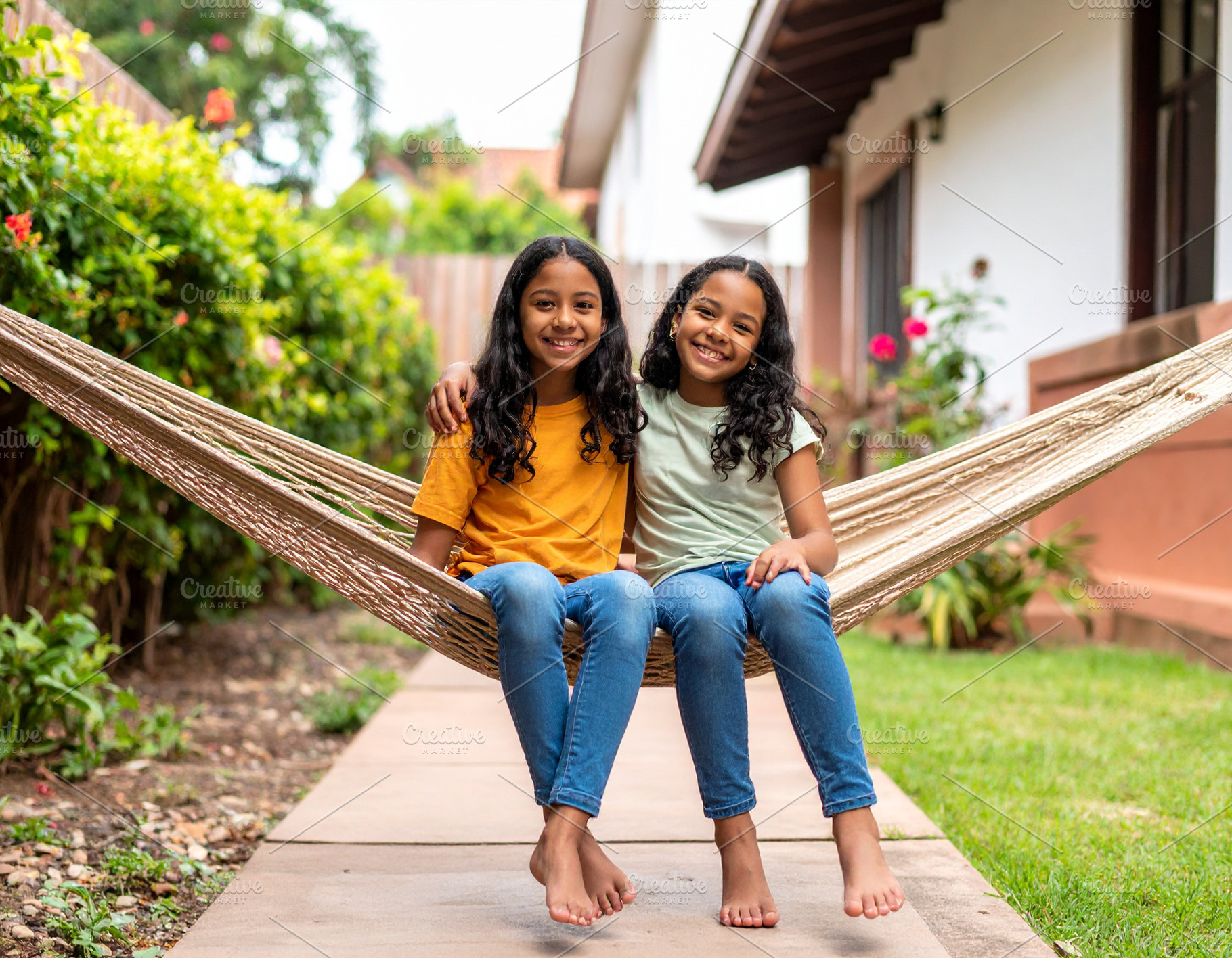 Two girls sitting together on a hammock in the backyard of a hou, a Person Photo by DanFLCreativo