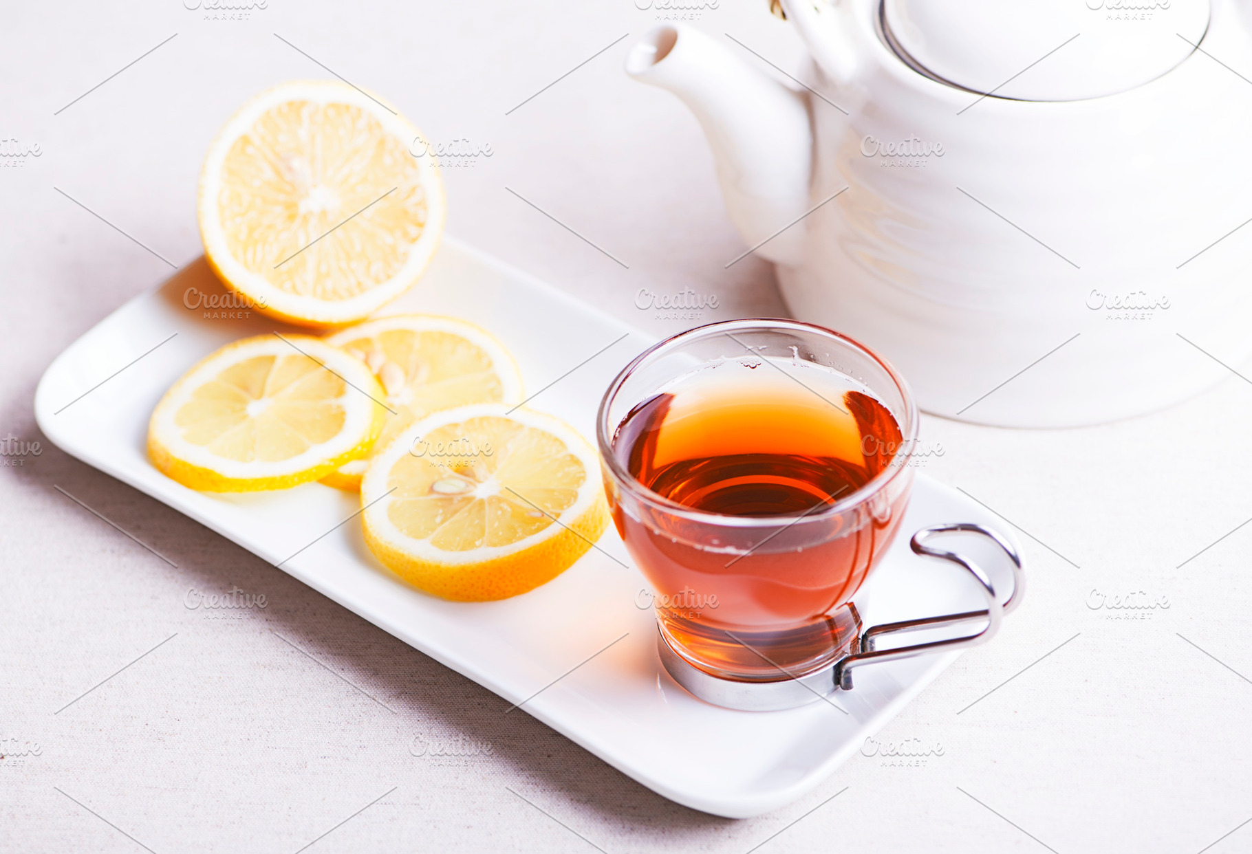 Tea cup with lemon on white plate next to teapot infusion featuring torch, a Food & Drink Photo by José Luis Agudo