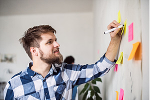 Man writing ideas on colorful sticky, a Business Photo by HalfPoint