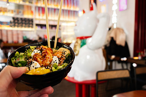 Close-up of a colorful poke bowl with shrimp in a vibrant restaurant setting, a Photo by AS photostudio