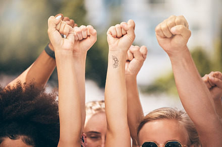 Protest, group and fist of people, hands in air for solidarity, equality and power women together outdoor. Diversity, strong and motivation people in crowd support of freedom revolution and justice, a Photo by Peopleimages.com