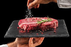 Chef is salting raw ribeye steak, a Food & Drink Photo by Volff