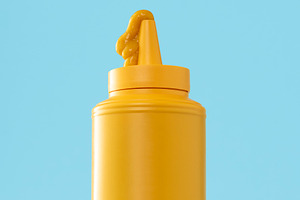 Mustard plastic bottle isolated on a blue background.