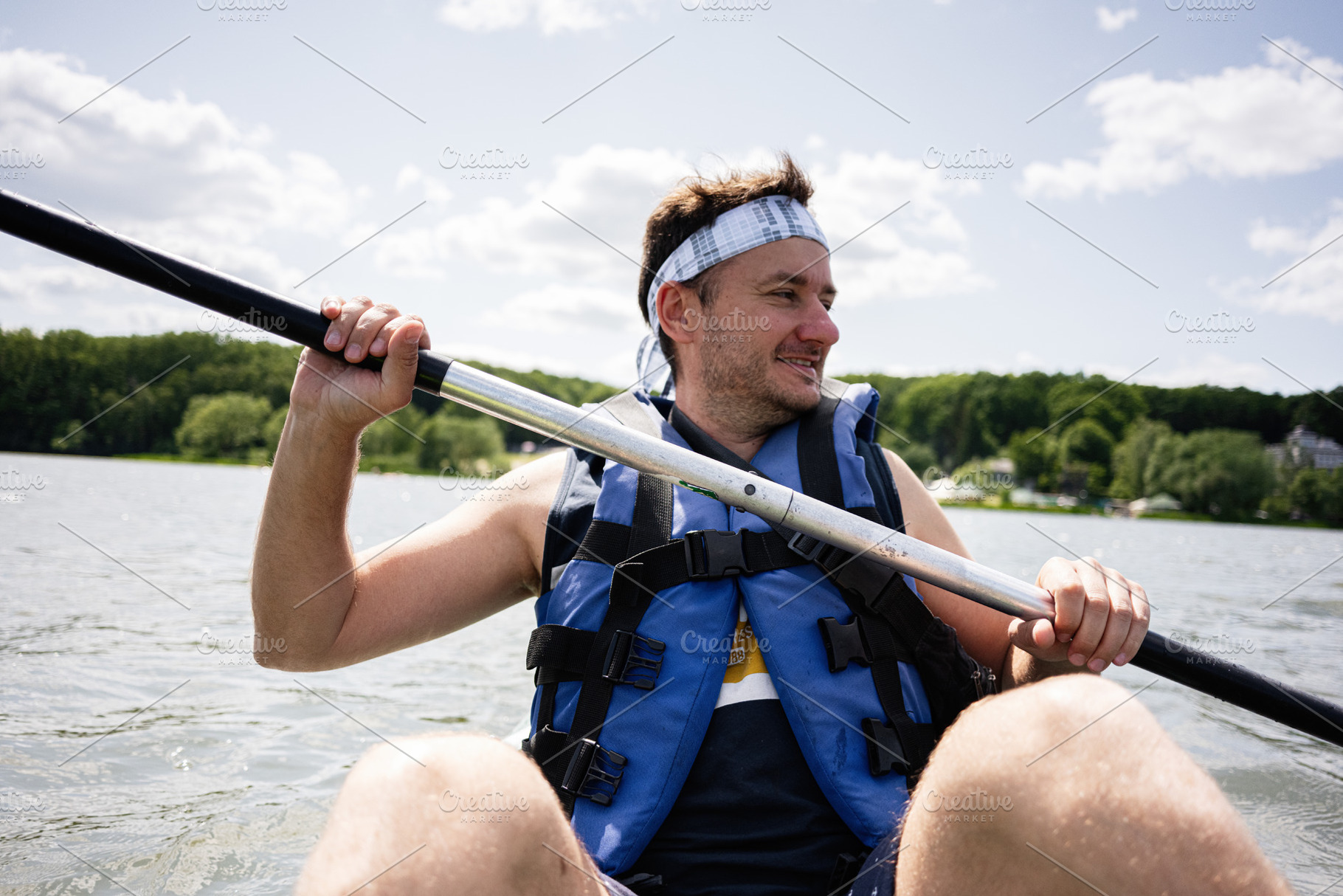 Man in life jacket kayaking on a serene lake, enjoying nature and sunshine, a Photo by AS photostudio
